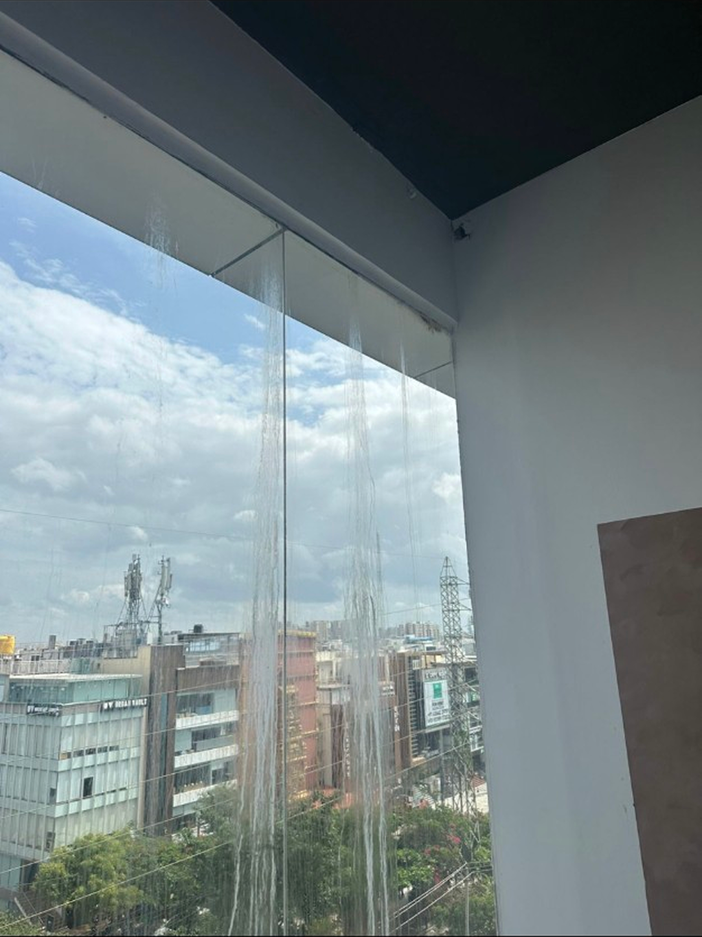 Before — calcium carbonate streaking on commercial glass facade Bangalore